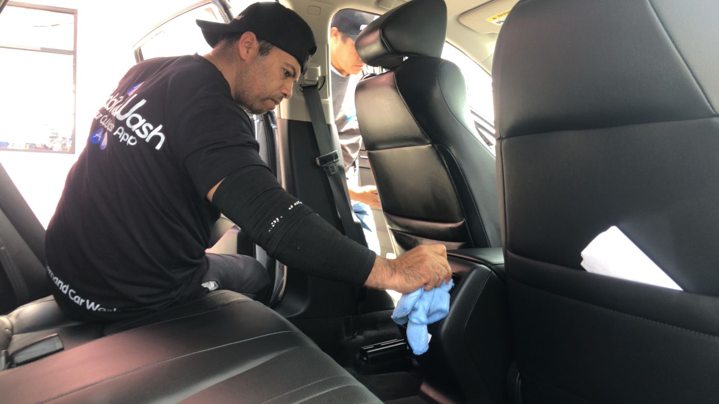 A microfibre cloth wiping the black plastic of a rear seat console